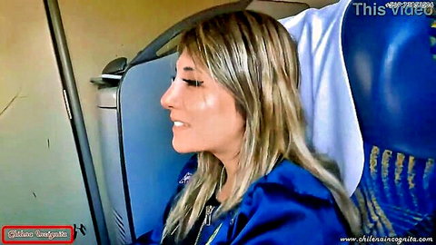Blonde woman in blue jacket smiling on bus seat, public risky tease