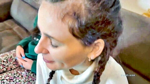 Two women on couch, one with braids in white top, other in green, casual pickup scene