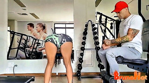 Blonde babe bends over in tight green leggings, teasing big ass while man watches in gym