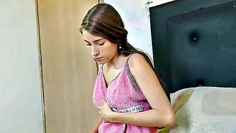 Young brunette stepsister holding pink towel, stripping seductively in bedroom