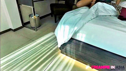 Perky Thai teen lying on bed post-creampie, legs parted seductively