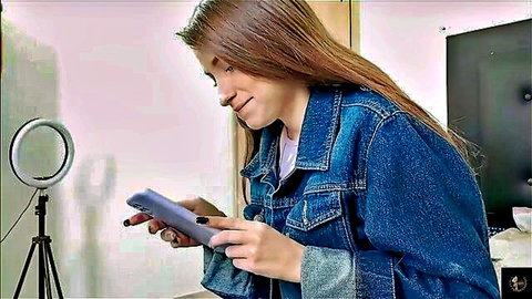 Brunette amateur model in denim jacket holding phone, smiling seductively