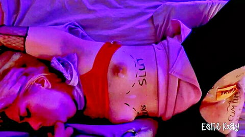 Estie Kay tied up, exposed tits marked 'slut' and 'cum dump' in fishnets at party
