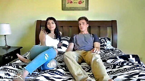 Latina beauty in white tank top and ripped jeans with handsome guy on bed