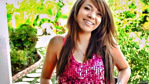 Cassidy Banks smiling in pink sequin top, showing cleavage outdoors