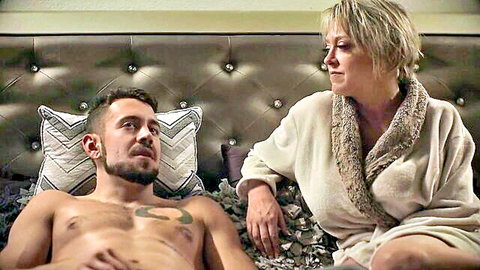 Dee Williams in robe with shirtless young man on bed, mom-son fantasy