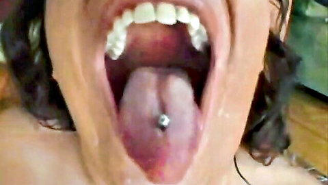 Caucasian woman with curly hair and tongue piercing opens mouth wide for cumshot