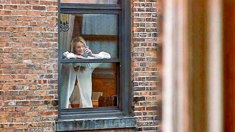 Sexy blonde leaning out window on phone call teasing with open blouse