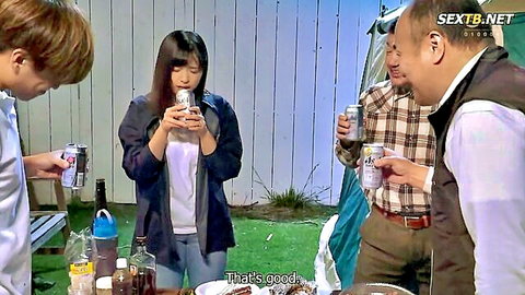 Japanese MILF wife smiles holding beer can with husband and friend at campsite picnic