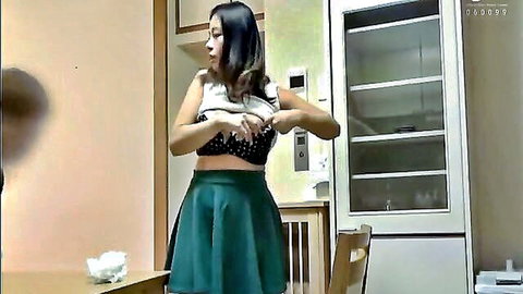 Asian woman adjusting revealing white top and green miniskirt