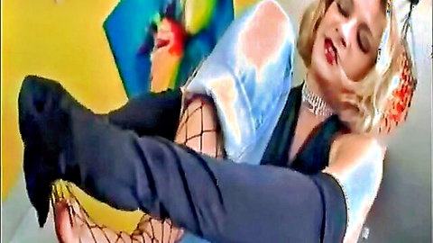 Blonde in fishnet stockings teases with soles in foot fetish pose