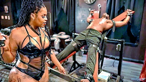 Ebony femdom mistress in latex lingerie dominating bound submissive man with paddle