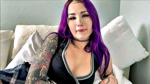 Valerica Steele with purple hair and tattoos in low-cut black tank top