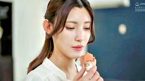 Asian woman in white blouse holding orange food near lips, soft teasing expression