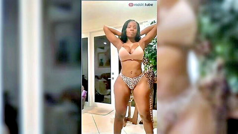 Curvy ebony woman in skimpy bikini posing with arms raised