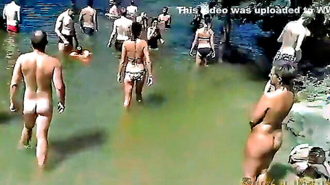 Nudist camp at lake with nude men and women swimming outdoors