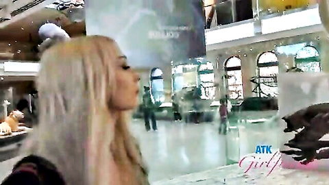 Long-haired blonde teen glancing sideways in luxury mall wearing tight black top