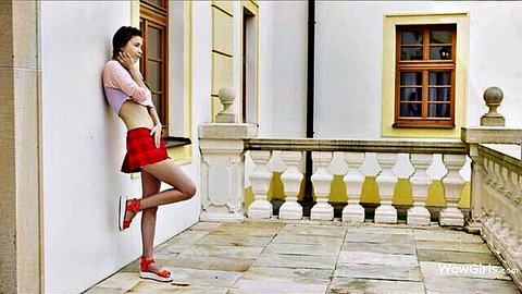 Skinny brunette teen in pink crop top showing underboob and red mini skirt posing seductively outdoors