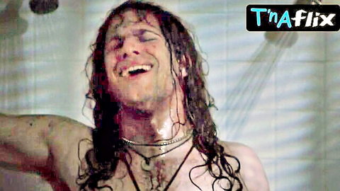 Wet long-haired muscular stud grinning in ecstasy under shower stream