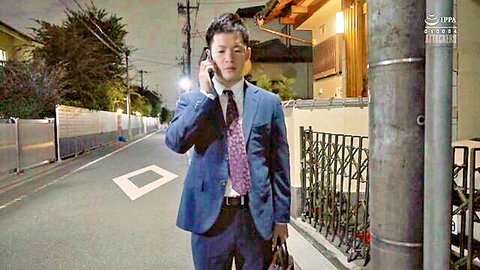 Japanese businessman in blue suit talking on phone at night outside house