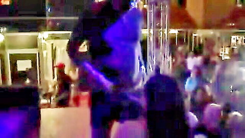 Blurry crowded nightclub scene with woman in shiny dress dancing close to man under purple lights