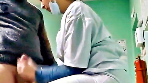 Arab nurse in white uniform strokes patient's erect cock with gloved hand in medical room