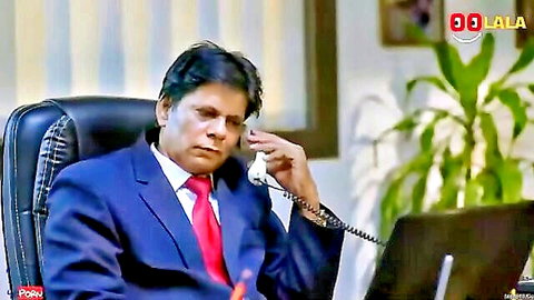 South Asian businessman in blue suit and red tie talking on office landline phone