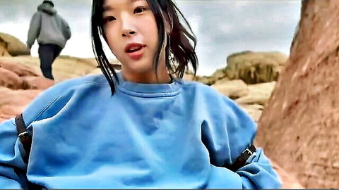 Petite Asian babe in oversized blue hoodie posing seductively outdoors on red desert rocks