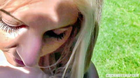 Seductive blonde woman with eyes closed and pouty lips outdoors on green grass