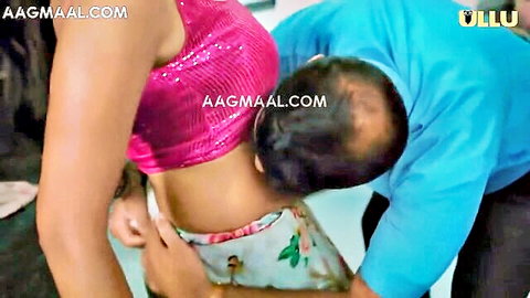 Busty Indian brunette in sparkly pink top kissed on neck by man from behind grabbing her waist
