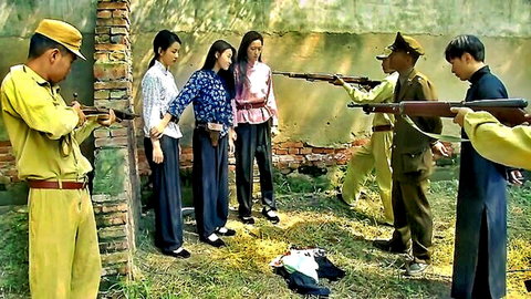 Japanese soldiers in yellow uniforms point rifles at surrendering Chinese women outdoors by brick wall