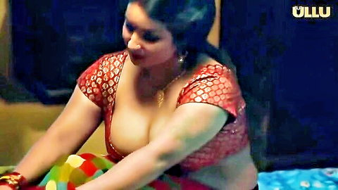 Curvy Indian woman in red saree blouse with deep cleavage on bed