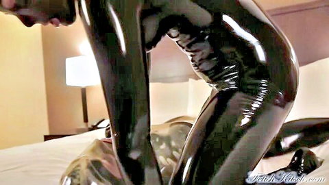 Shiny latex lesbians in BDSM play, one bent over doggystyle exposing tight catsuit ass to domme