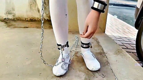 Slim Asian woman in white stockings and chains for outdoor BDSM bondage walk