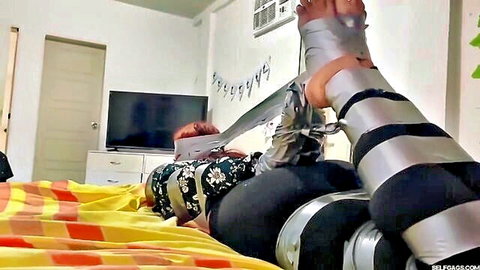 Redhead bound with duct tape and chains on legs in BDSM