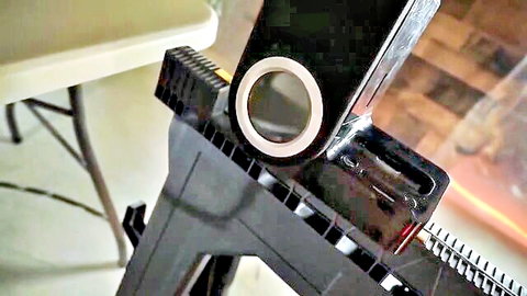 Black plastic BDSM-style clamp holder with white rings on beige folding table