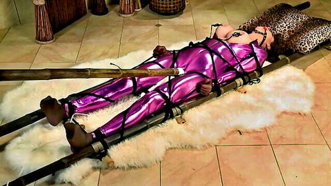 Christina Carter bound in shiny purple latex with ropes and gag in BDSM scene