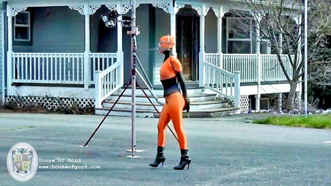 Cherry Torn in orange latex catsuit and helmet, BDSM outdoor scene