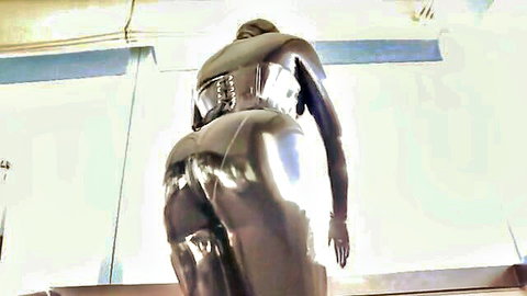 Curvy woman in tight shiny black rubber catsuit, emphasizing big ass in BDSM pose