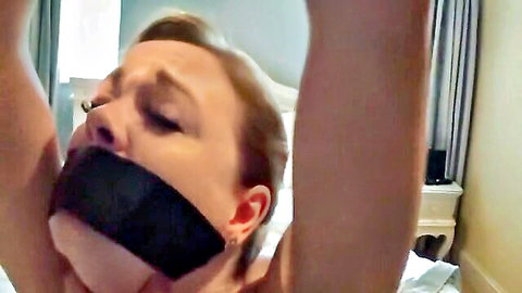 Blonde woman gagged in BDSM bondage, eyes closed in ecstasy