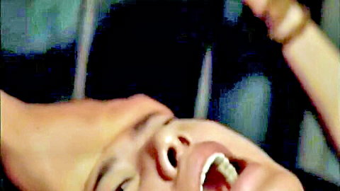 Asian woman hand gagged with mouth forced wide open in intense BDSM scene