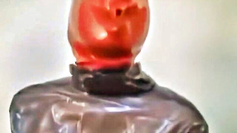 Shiny red latex hood covers woman's face in glossy rubber catsuit BDSM fetish gear