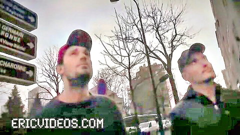 Two bearded men in caps on urban street, teasing rough gay threesome
