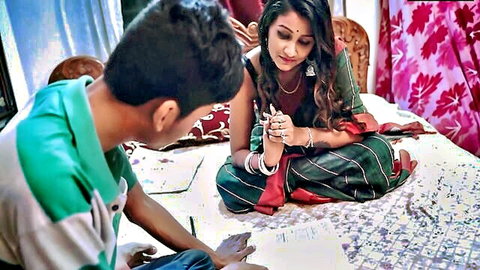 Indian woman in saree watches young man writing on bed in bedroom