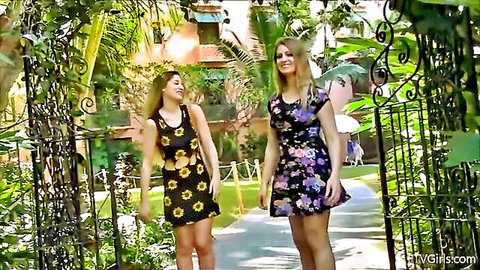 Two sexy blondes in short floral dresses tease upskirts walking through tropical resort gate