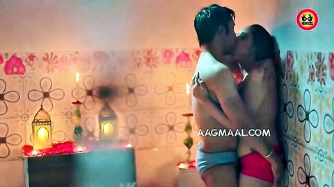 Shirtless Indian stud passionately kisses busty brunette MILF in red bra-pink panties against tiled wall