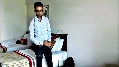 Handsome Indian man in white shirt and black pants sitting on bed, gay porn teaser