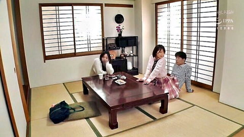 Three clothed people sitting around a low wooden table in a traditional Japanese tatami room.