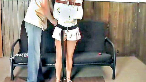Skinny bound brunette MILF in tiny white skirt lifted exposing ass groped by man in BDSM bondage