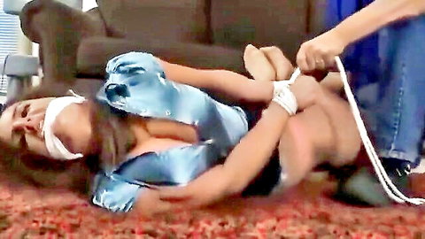 Bound brunette in satin dress gagged and tied up by man in BDSM scene